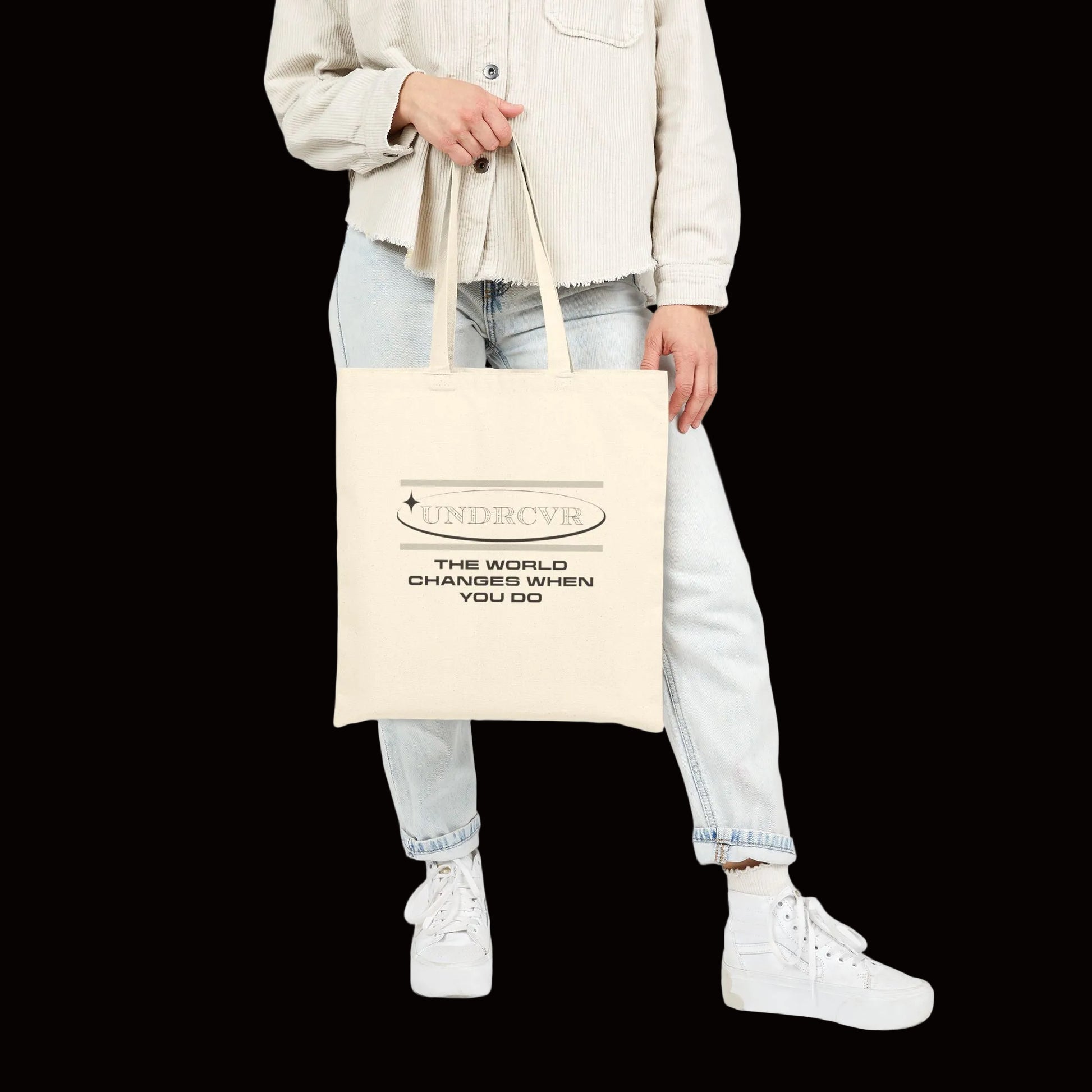 Person holding a beige tote bag with a design on a white background