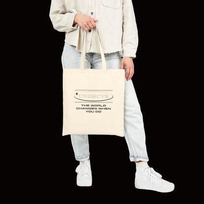 Person holding a beige tote bag with a design on a white background