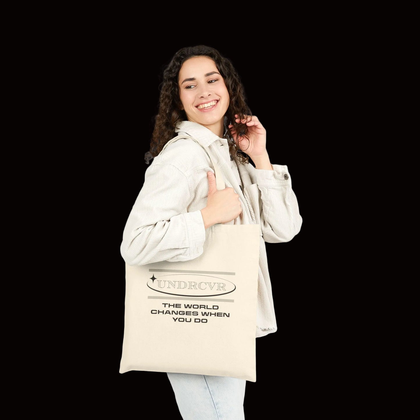 Woman holding a tote bag with 'The Homebody Club' text on a white background